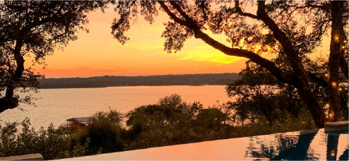 A sunset over the water with trees in front of it.